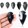 A set of natural black obsidian arrow pendants displayed on a hand.