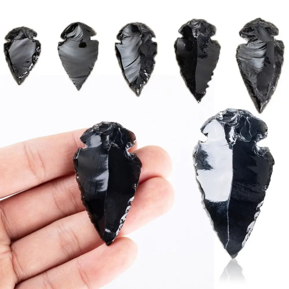 A set of natural black obsidian arrow pendants displayed on a hand.