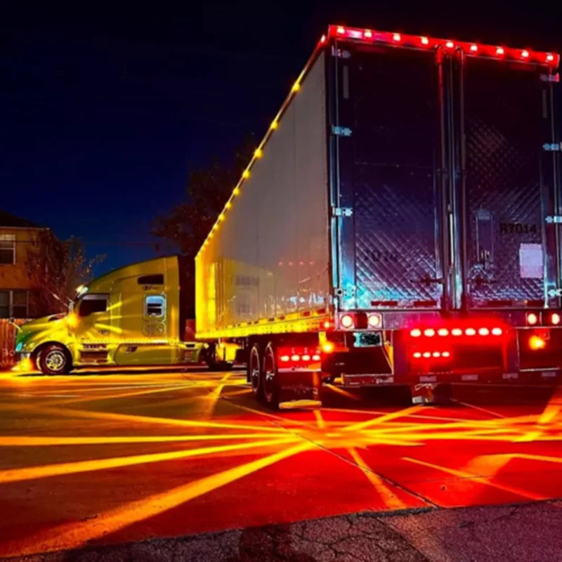 A large truck with bright LED side marker lights illuminating the road at night.