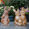 A hand-painted resin garden statue of three adorable brown rabbits sitting together.