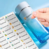 A hand is squeezing a blue bottle of Quennel waterproof name stickers onto a sheet of stickers.