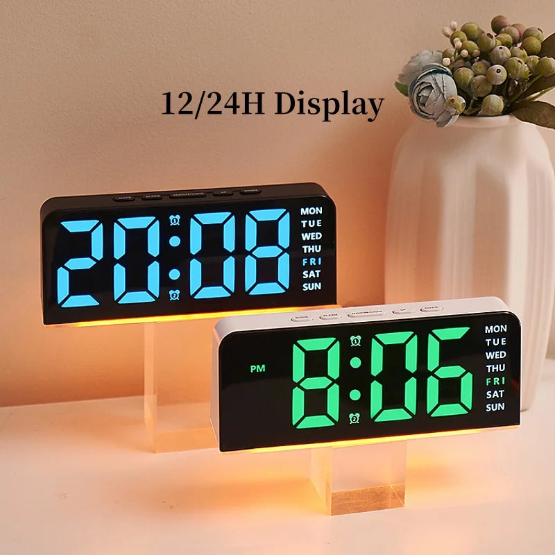 A black digital alarm clock displaying 20:08 on a wooden stand, with an accompanying white vase and greenery.