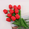 A bouquet of vibrant red artificial tulips with green stems and leaves.
