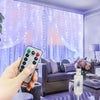 A hand holds a smartphone in front of purple LED curtain lights illuminating a window with sheer fabric.