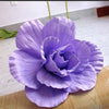 A vibrant purple silk foam rose flower in full bloom displayed on a wooden surface.