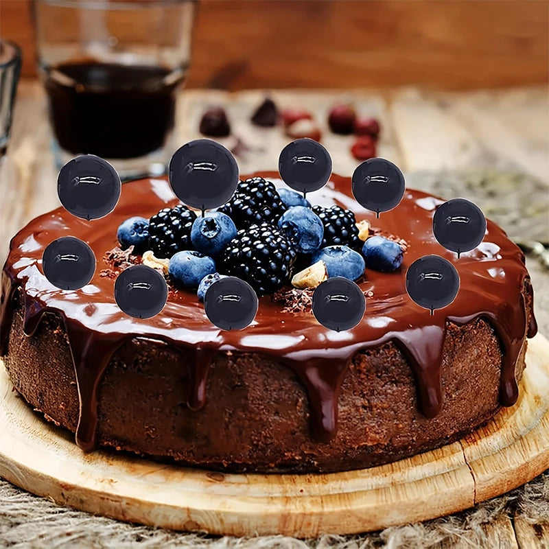 A round chocolate cake topped with fresh blueberries and blackberries, served on a wooden board.