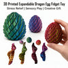 A hand holds a green dragon egg fidget toy and several twisted, colorful plastic dragon egg ornaments.
