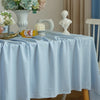 A light blue cotton rectangle tablecloth is set on a table with floral arrangements and decorative items.