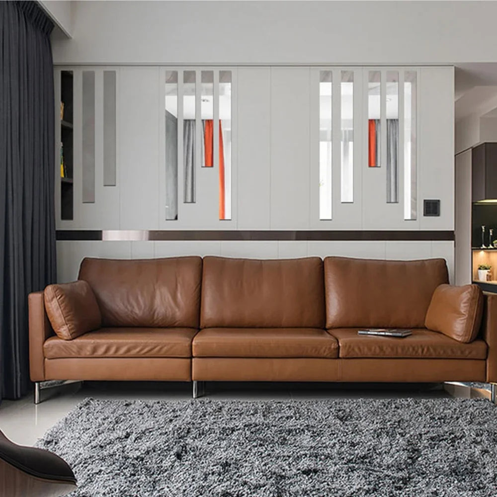 A modern living room featuring a brown leather sofa in front of white mirrored wall panels and a gray rug.