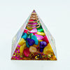 A pyramid structure made of various colored crystals, including amethyst and quartz, with a gold coil at the apex.