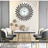 A modern minimalist metal wall clock with a black face hangs on a light wall above a glass table.