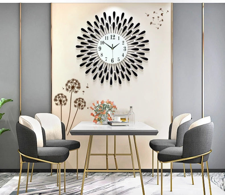 A modern minimalist metal wall clock with a black face hangs on a light wall above a glass table.