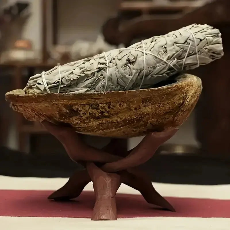 Vintage wooden tripod stand holding a rolled, textured object, likely an abalone shell or crystal ball display.