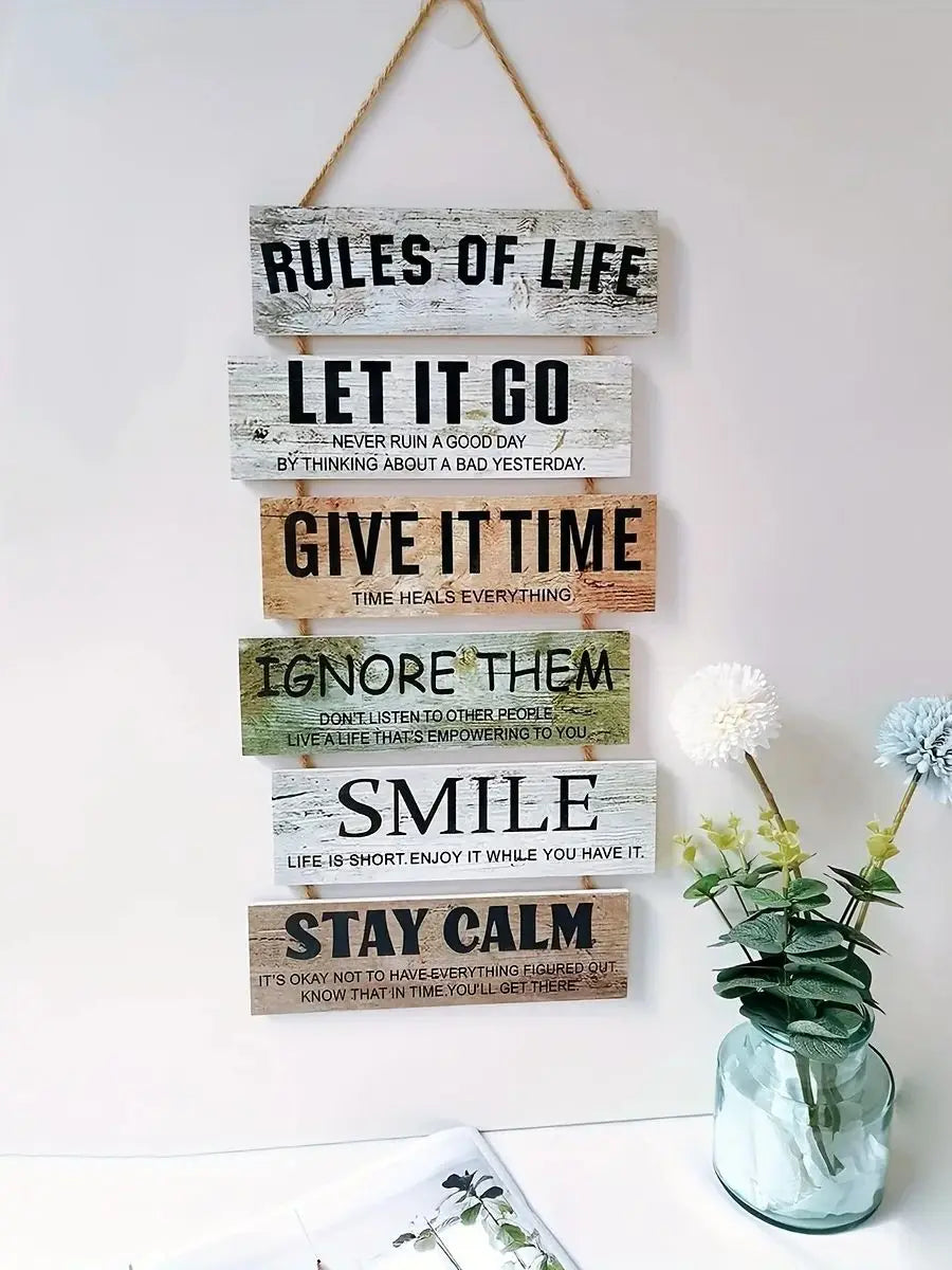 A vertical display of wooden inspirational signs with text like Rules of Life Let It Go Give It Time Ignore Them Smile and St