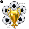 A gold trophy balloon with the number 1 is surrounded by black and white soccer balls for a party decoration.