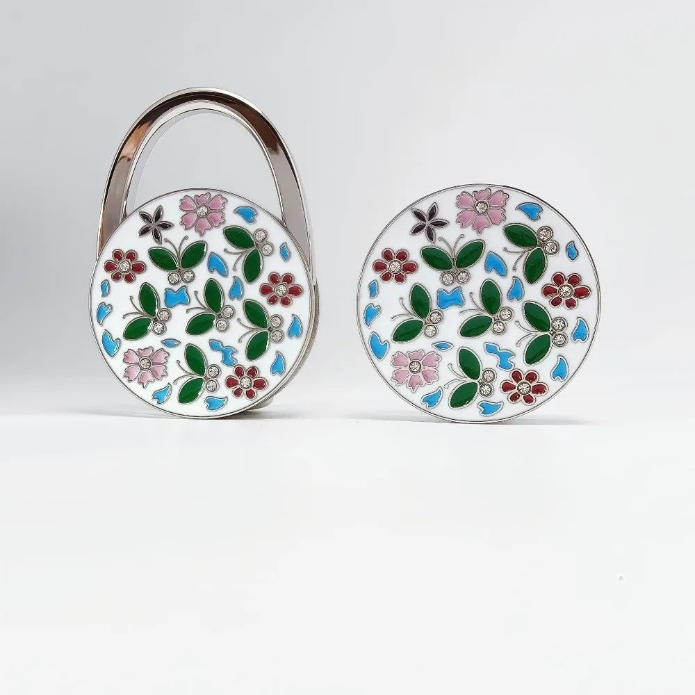 Silver handbag hook with a round floral crystal design featuring pink, green, and blue flowers