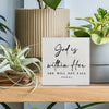 A wooden sign with the scripture God is within her she will not fall from Psalm 46:5 displayed on a light wood shelf.