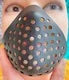 A close-up of a realistic horror animal mask with small holes and dots being held by a hand.
