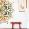 Gros plan d'un mur avec un grand motif de lotus mandala doré et brun complexe.