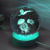 A crystal ball night light featuring a glowing jellyfish and a silhouette of a flying creature against a dark background.