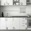 A white kitchen cabinet and countertop featuring decorative wall stickers of kitchen utensils.