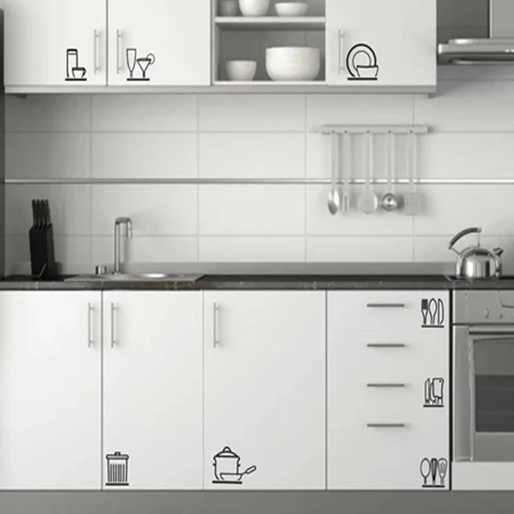 A white kitchen cabinet and countertop featuring decorative wall stickers of kitchen utensils.