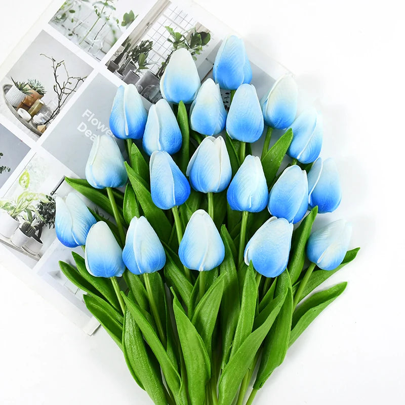 A bouquet of light blue and white artificial tulips with green stems and leaves.