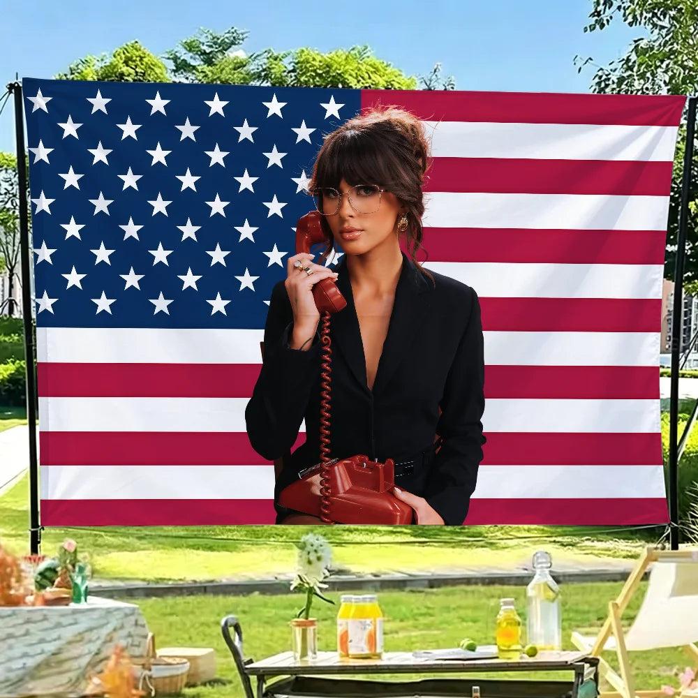 A woman wearing glasses and a black shirt poses in front of a large American flag backdrop.