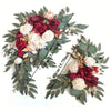 A floral kit featuring deep red and blush roses mixed with white flowers and dusty green eucalyptus leaves.