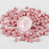 A pile of pink transparent wax sealing beads for custom stamps.