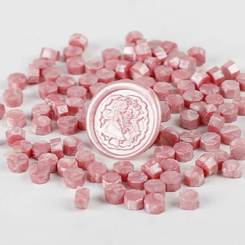 A pile of pink transparent wax sealing beads for custom stamps.