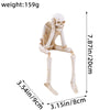 A white resin skeleton skull figurine with elongated limbs and a small decorative element.