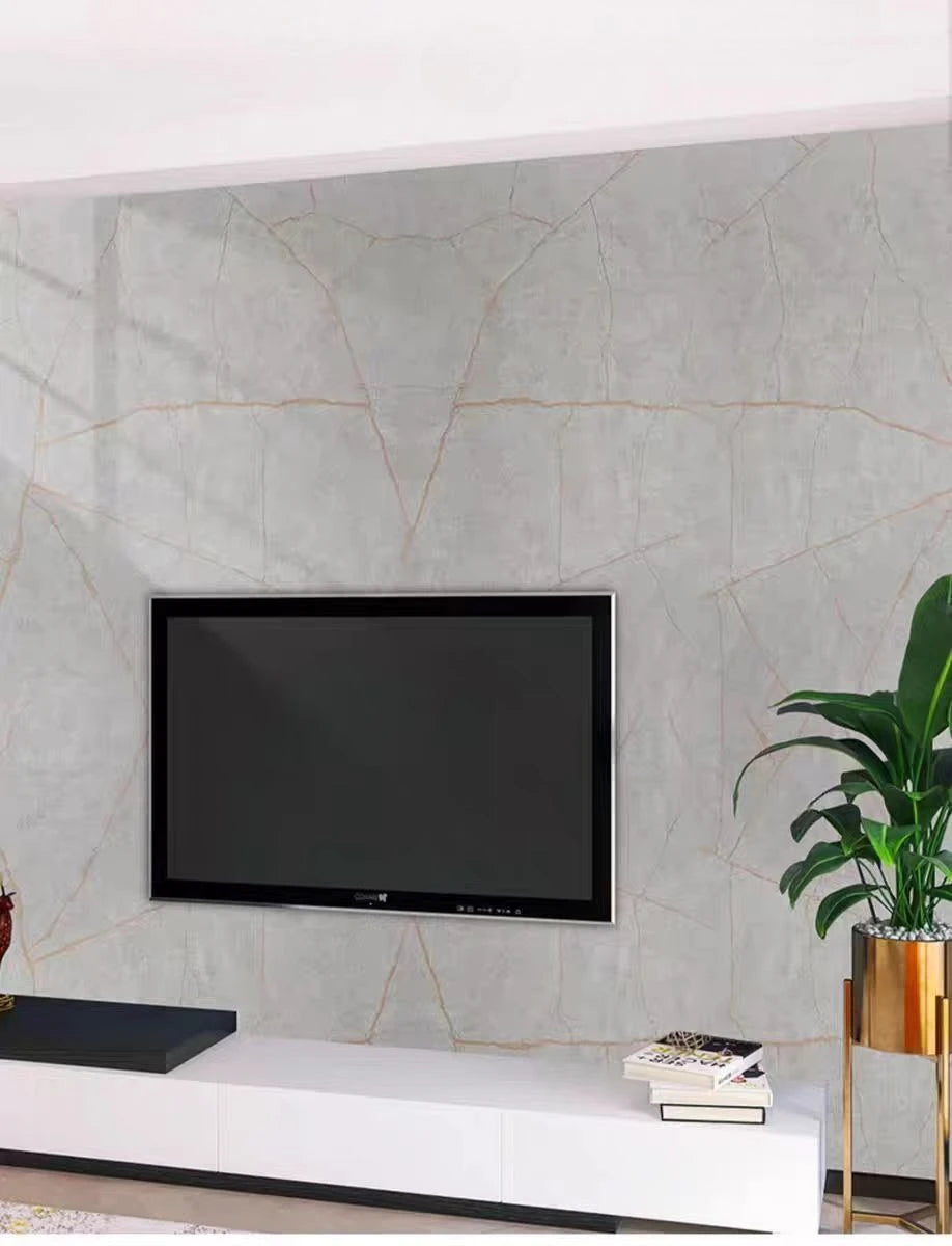 A flat-screen television mounted on a gray marble-patterned wall above a white cabinet.