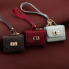 A set of mini leather openable bags in maroon, dark green, and light gray with gold hardware.