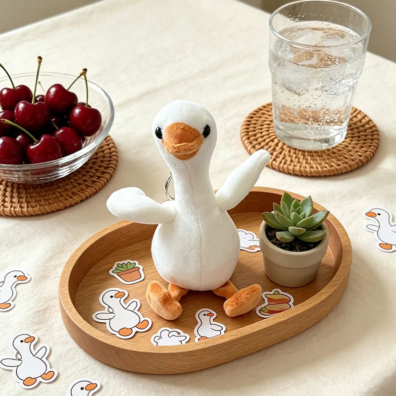 A white duck plush toy sitting on a wooden tray with small cutout shapes and a glass of water.