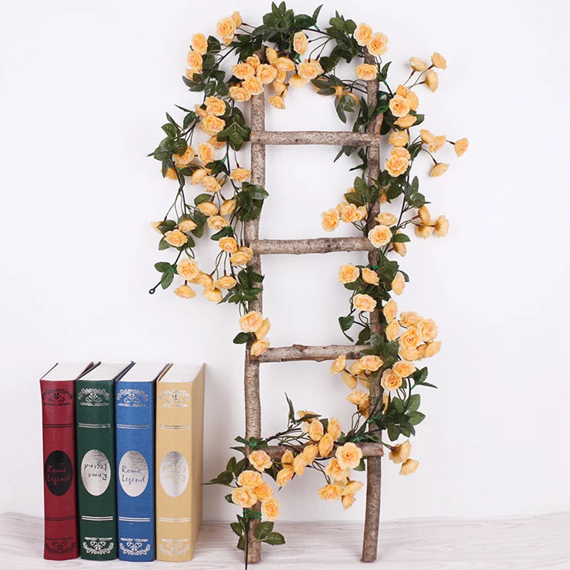 A rustic wooden ladder decorated with a silk rose vine garland featuring yellow roses and green leaves.