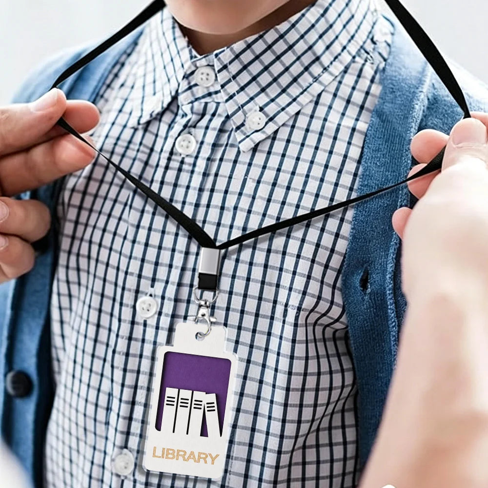 A person is wearing a black lanyard with an acrylic hall pass tag that reads LIBRARY.