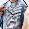 A person is wearing a black lanyard with an acrylic hall pass tag that reads LIBRARY.