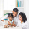 A woman and a child are counting coins in a transparent piggy bank on a white table.