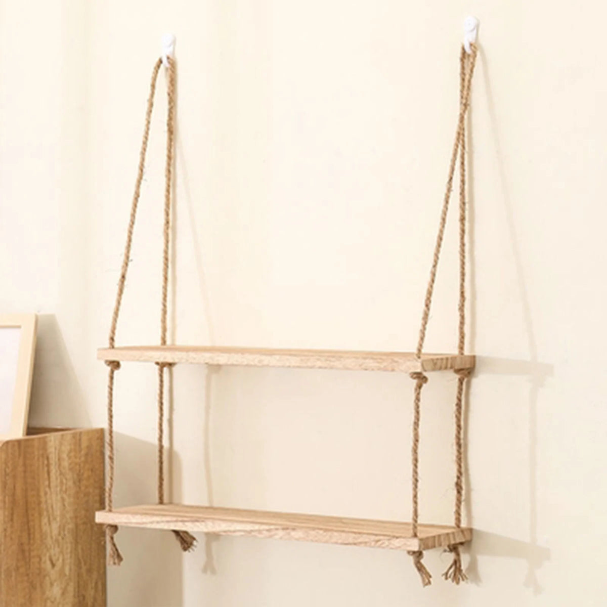 Rustic wooden hanging shelves with rope mounted on a light-colored wall.