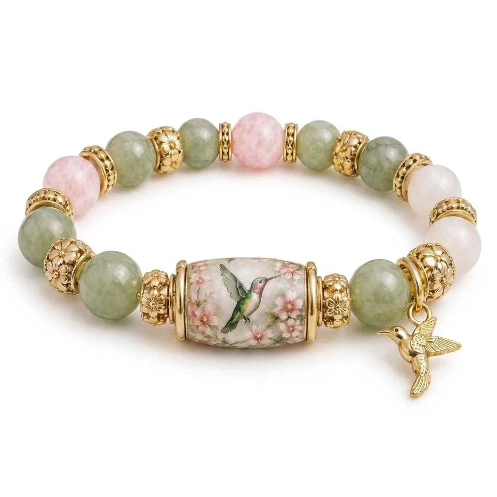 A stretch charm bracelet featuring round beads of pink and green stones set in gold-toned metal with a bird charm.