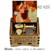 A wooden music box featuring a couple, with an open lid revealing the internal mechanism.