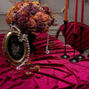 A burgundy red velvet rectangular tablecloth set for elegant dining with a floral arrangement and candles.