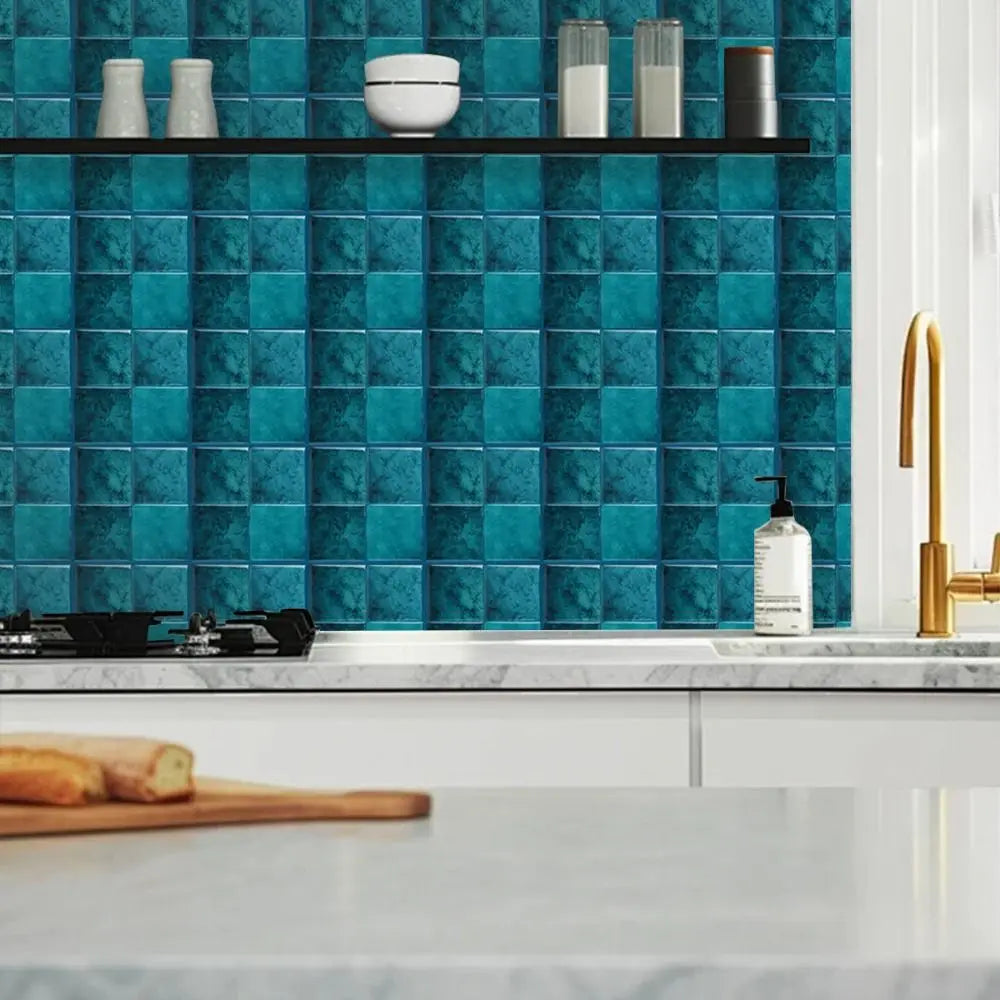 A kitchen backsplash featuring teal square marble tiles and a dark shelf with white ceramic items.