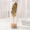 A gold-colored iron ginkgo leaf ornament mounted on a wooden base.
