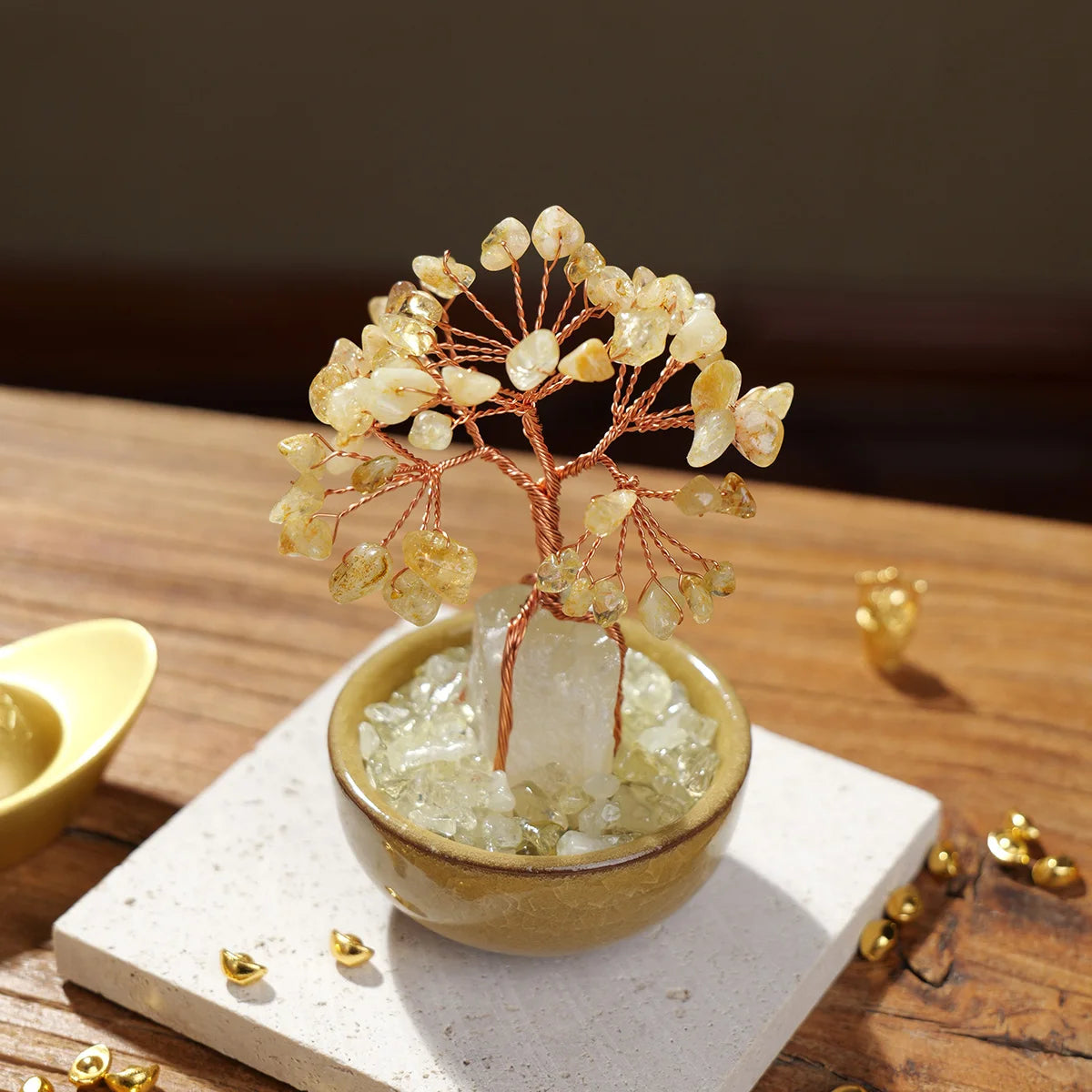 A small natural crystal money tree with a rose quartz base sits on a light surface.