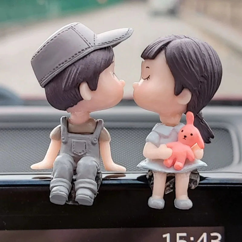 A figurine of a girl and a boy with a balloon, displayed on a car dashboard.