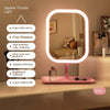 A pink square tricolor light vanity mirror with a round LED frame and a pink stand.