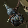 A dark blue ceramic wine gourd with a stopper is suspended by twine, used for hot water or beverages.