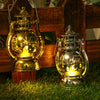 A brass LED lantern night light with a warm glow and decorative patterns sits on a wooden surface.